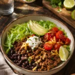 High protein taco meal prep bowls with ground beef, black beans, cheddar, lettuce, and pico de gallo